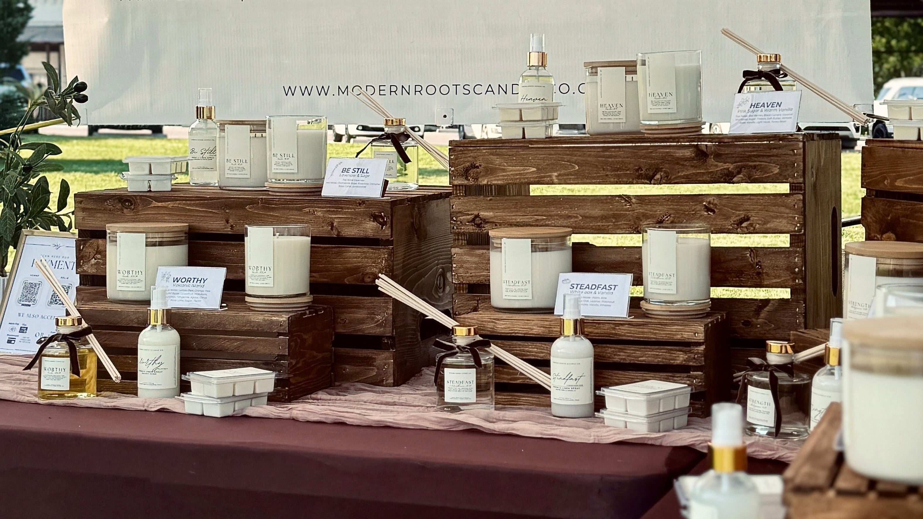 Display of candles and products by Modern Roots Candle Co. with a branded backdrop.